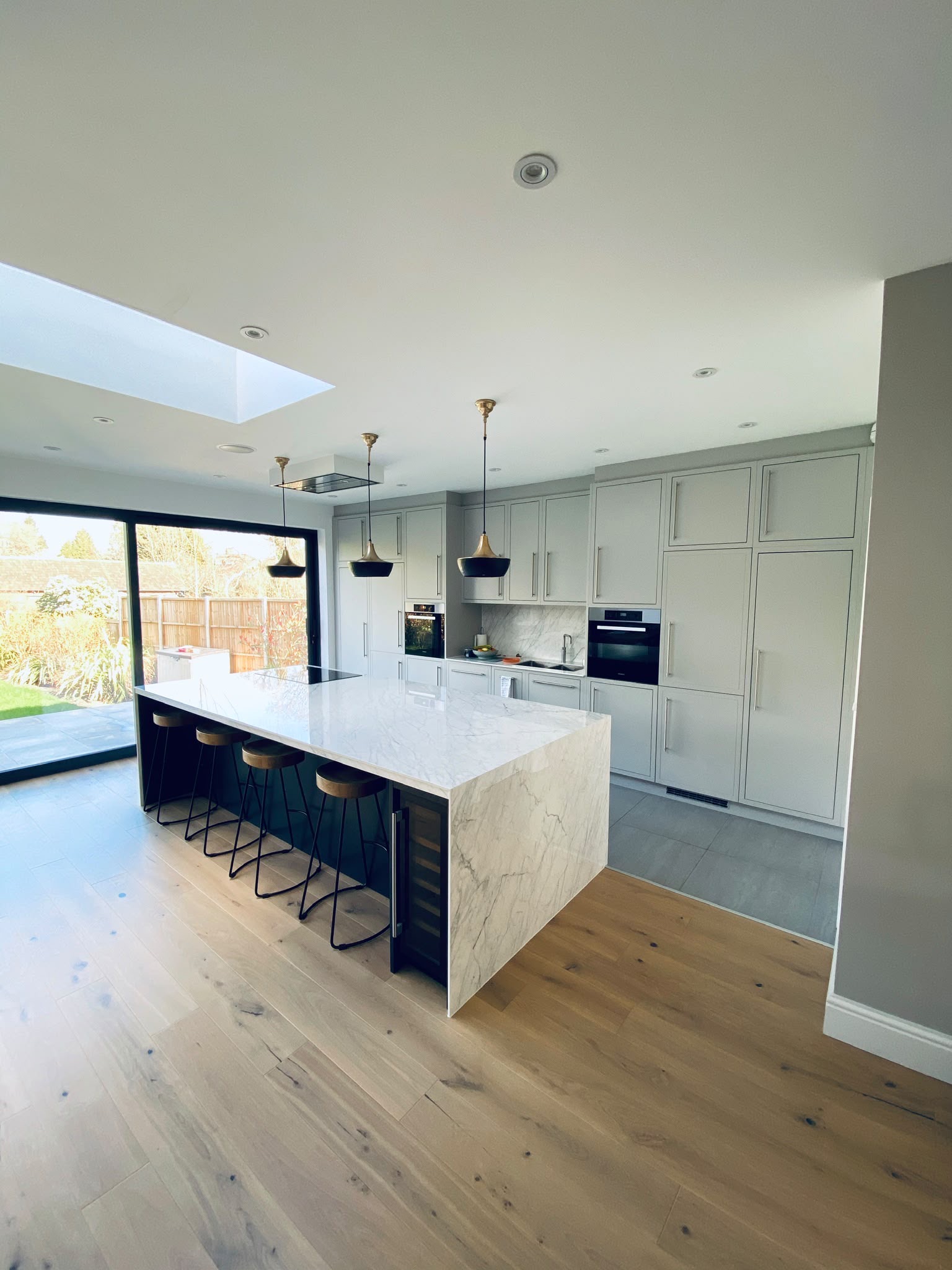 Contemporary dark kitchen with central island and bespoke slatted ceiling